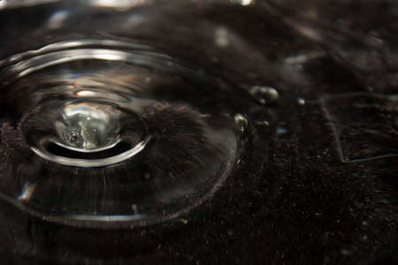 Sphere drop of water falling into a ring that forms on the surface of clean waterの写真素材