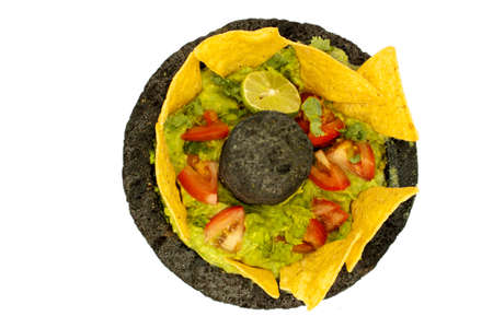 Top view avocado dip with lemon, garlic, coriander, tomato garnished with chips in a stone bowlの写真素材