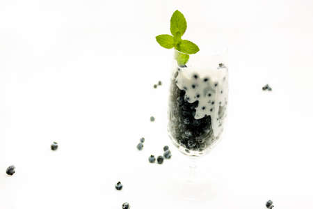 Glass cup with blue berries served with yogurt and a touch of mintの写真素材