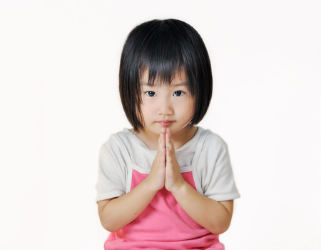 asian small child pay respect by pressing the hands together at the chest on white backgroundの写真素材