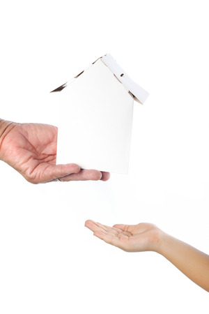 Old woman's hand giving paper home to child; concept of inheritanceの写真素材