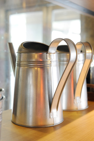 aluminum watering cans on wooden shelfの写真素材