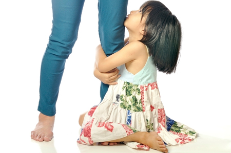 little asian girl looking up and holding her mother leg isolated on white backgroundの写真素材