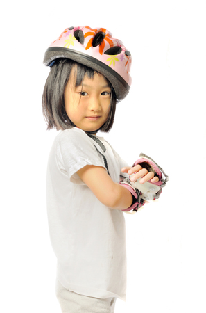 asian little girl in protective roller gear on white backgroundの写真素材