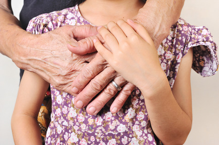  hand of senior hugging with her child. hand of a child embrace the hands of an old woman with love