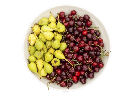 Bowl of organic cherries and pears on white background