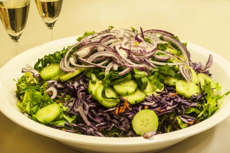 Mixed salad dish with white wine glassesの写真素材