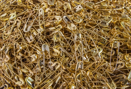 Gold colored safety pins pile closeup as backgroundの写真素材