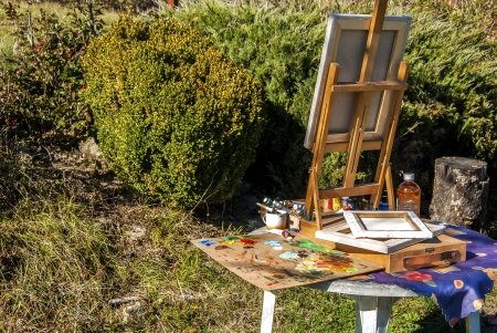Tabletop easel for painting, palette, canvas, paint and other drawing materials artist equipment set ready for work in gardenの写真素材