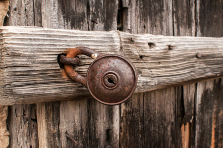 Old rusty padlock on weathered wooden door closeupの写真素材