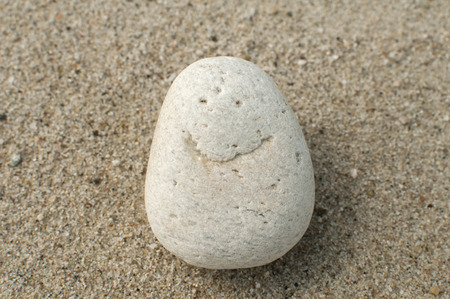 Naturally received image of smile on sea pebble stone on sand backgroundの写真素材