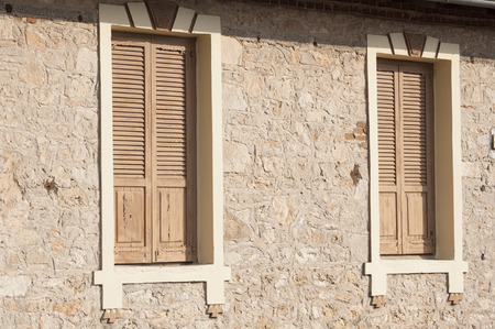 Two closed wooden windows on stone house wallの写真素材