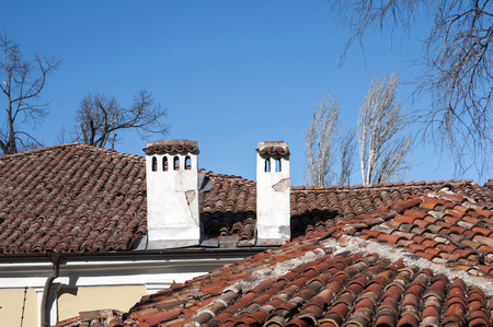 Roofs and chimneys of old houses on blue sky backgroundの写真素材