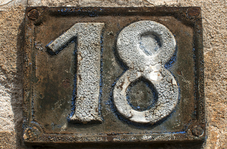 Old retro weathered painted cast iron plate with number 18の写真素材