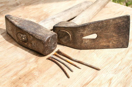 Old weathered grunge hammer, adze and rusty nails closeup on plywood surfaceの写真素材