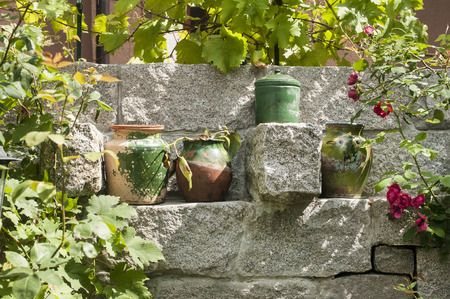 Clay pots of flowers placed in niche of stone garden wallの写真素材