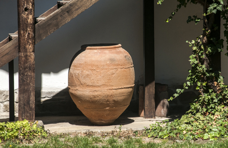 Big old clay cruse under old wooden house ladderの写真素材
