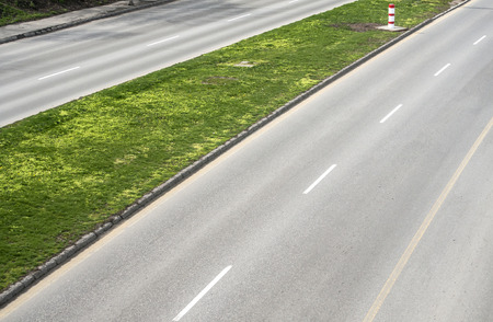 Part of asphalt motor road with dividing strip of green grassの写真素材