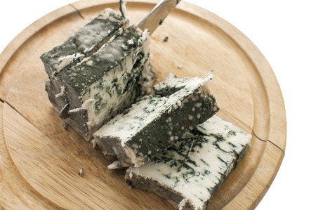 Sliced moldy lump of white cheese and knife on wooden tray isolated on white backgroundの写真素材