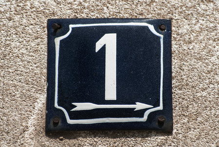 Weathered grunge square metal enameled plate of number of street address with number 1 closeup