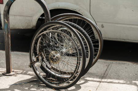 Used bicycle wheels locked to street poleの写真素材