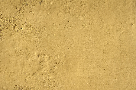 Ocher house rough plastered facade wall closeup as backgroundの写真素材