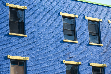 Old vintage blue painted brick urban house facade with windows