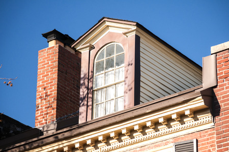 Attic window and chimney closeup on vintage red brick building topの写真素材