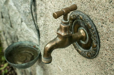 Old vintage brass water tap of stone fountain closeupの写真素材