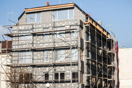 Building under construction with scaffolding for affixing the heat insulationのeditorial素材