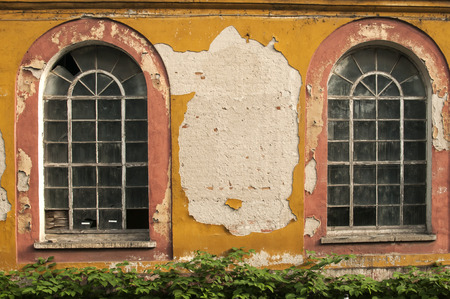 Old vintage weathered crumbling grunge glass windows of abandoned industrial building