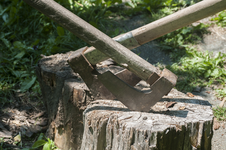 Old used weathered wooden axes stuck on wooden log for splitting wood into farmyardの写真素材