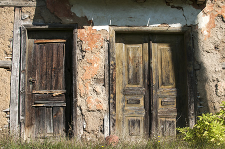 Old abandoned decayed grunge rural rickety house clay crumbled wooden weathered neglected doorsの写真素材