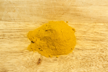 A pile of turmeric dry grounded powder closeup on wooden board backgroundの写真素材