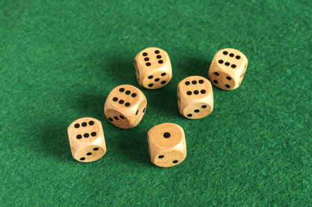 Wooden round corner dice six sided dots set for playing on dark green poker table felt cloth surface...