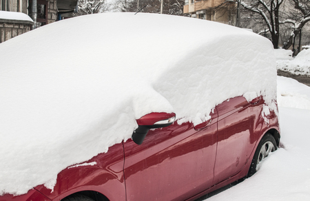 Parked car covered with thick layer of snow after blizzard in winter timeの写真素材