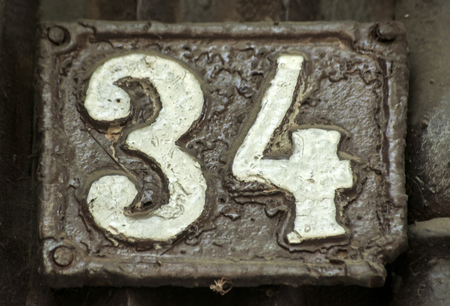 Old retro weathered cast iron plate with number 34 closeupの写真素材