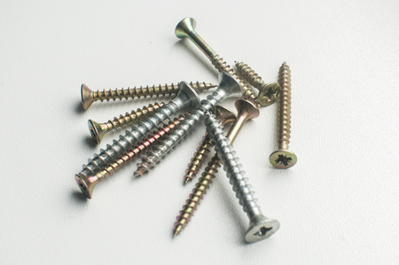 A pile of wood screws and screwdriver shaft head closeup on white backgroundの写真素材