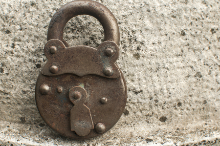 Old weathered grunge retro locked padlock closeup on solid stone surface backgroundの写真素材