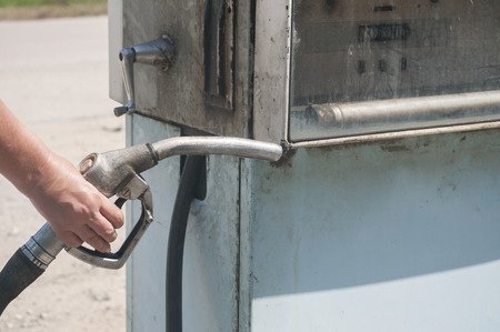 Old abandoned vintage obsolete petrol fuel gas dispenser in former petrol station and human hand holding petrol fuel dispenser handleの写真素材