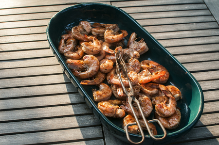 Ceramic dish with spicy grilled shrimps closeup on wooden rustic table background