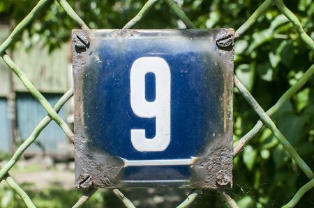 Weathered grunge square metal enameled plate of number of street address with number 9 closeupの写真素材
