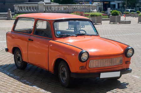 Orange colored vintage restored Trabant car on paved streetのeditorial素材