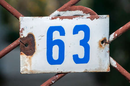 Weathered grunge square metal enameled plate of number of street address with number 63 closeupの写真素材