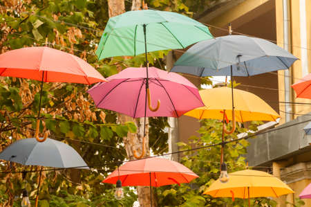 Umbrellas in different colors hanging over city streetの写真素材