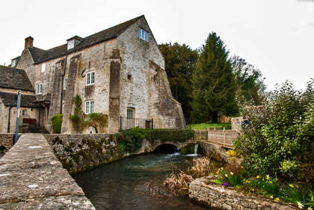 River passing old stone medieval houses in British provincial villageの写真素材