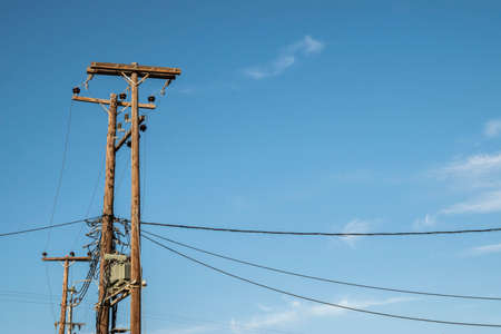 External transformer on wooden poles connected into electric energy on blue sky background