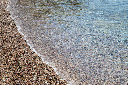 Clear calm sea waters meet pebble beach closeup as natural backgroundの写真素材
