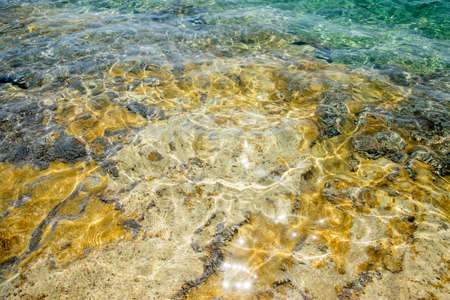 Rocky beach surface closeup through clear calm sea waterの写真素材