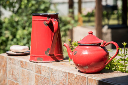 Old weathered red metal vintage teapot and kettle closeup outdoorの写真素材